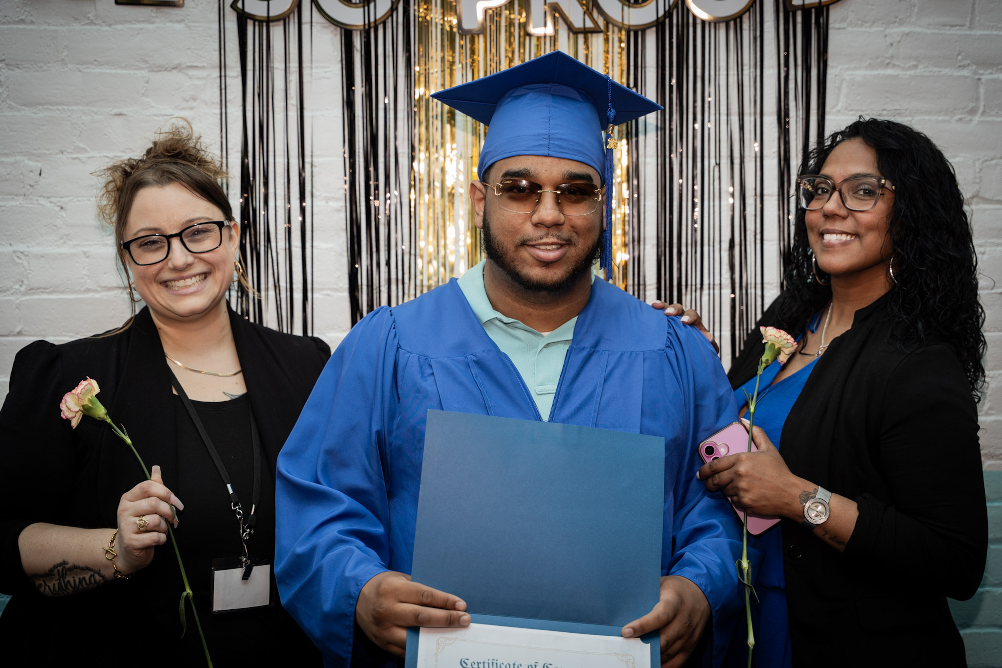 An ASCEND graduate holding his certificate with SCRIP team members
